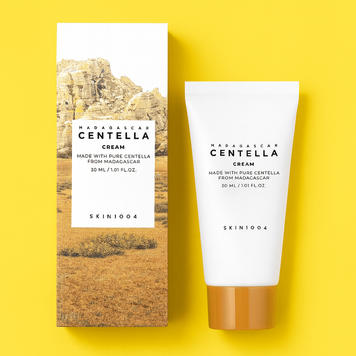Тюбик крема SKIN1004 Madagascar Centella Cream поруч з упаковкой на фоне с тёплым жёлтым оттенком. Натуральный дизайн, вдохновлённый природой Мадагаскара. Косметика для чувствительной и сухой кожи.